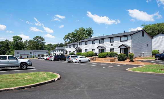 A parking lot with cars and a building in the background at The Madison Apartments and Townhomes, Georgia 30044