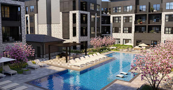 A swimming pool surrounded by lounge chairs and umbrellas in front of a building.