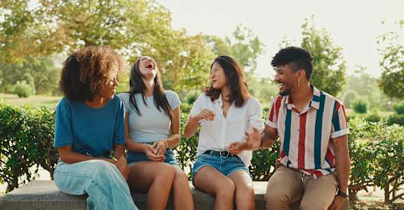 Four people are sitting on a bench outdoors at The Confluence Apartments, Easton, PA