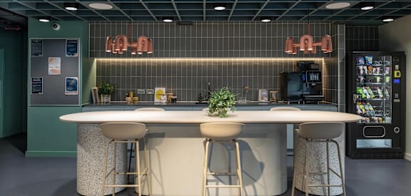 a communal table with four stools in a room with a vending machine