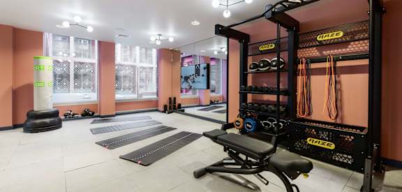 a home gym with weights and mats on the floor and a wall with a window