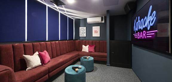 a cinema room with red couches and blue tables