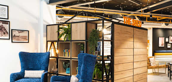 a lobby with blue chairs and a wooden cabinet