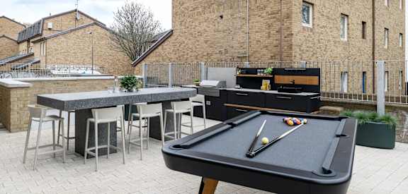a pool table in the outdoor seating area of a garden with a bar