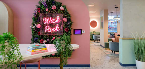 a pink wall with a chalkboard sign and a table with plants