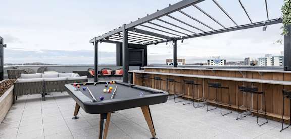 a pool table on a rooftop terrace with a bar