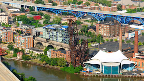 A bridge over a river with a white tent in front of a building.