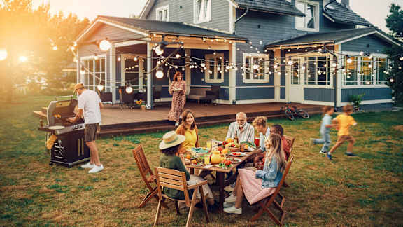 a group of people sitting around a table at a backyard party
