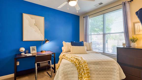 A bedroom with a bed, nightstand, and chair at Proximity at ODU, Virginia