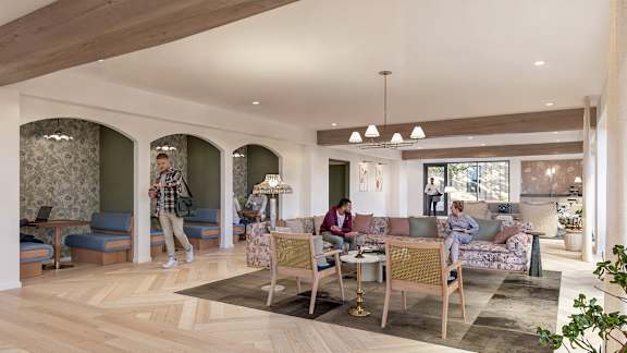 A man in a plaid shirt is walking through a spacious living room.