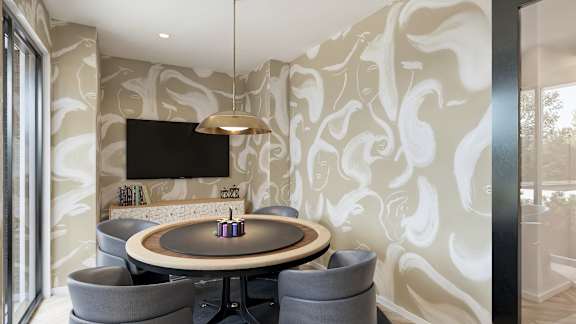 A modern dining room with a round table and grey chairs.