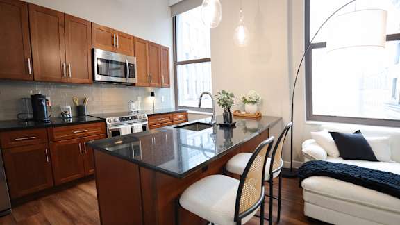 A modern kitchen with dark wood cabinets and a black granite countertop.