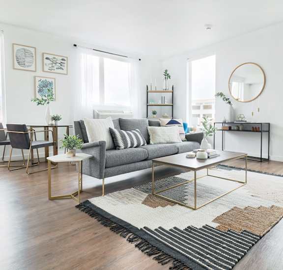 A living room with a grey sofa, a coffee table, and a large window. at The Fowler Apartments, Boise, ID