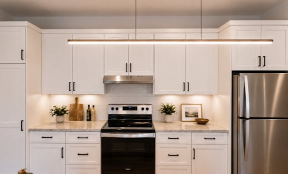 A kitchen with white cabinets and a wooden floor.