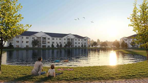 Lakeview Terrace apartment building in Ridgeland, SC featuring contemporary design, lush landscaping, and two people sitting in the grass.