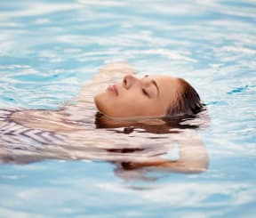 a young girl floating in a swimming pool