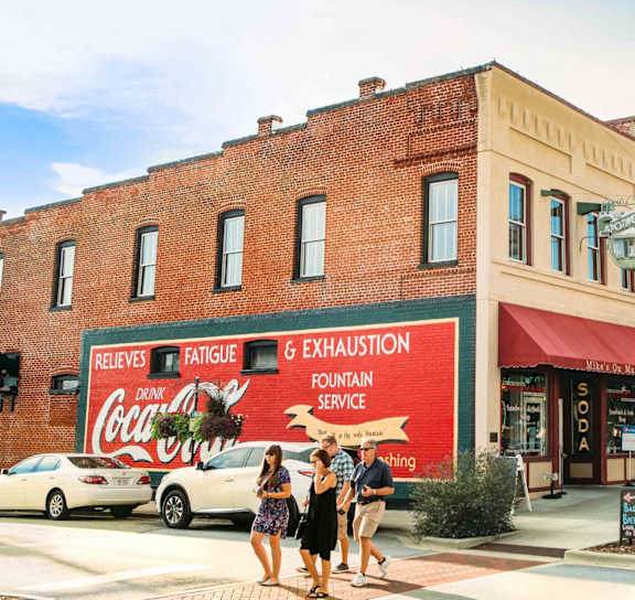 people walking down the street in front of a brick building