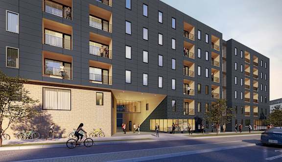 A modern apartment building with a bicycle rider in front.