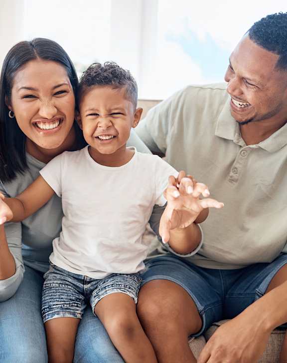 a family sitting on a couch smiling and waving to the camera