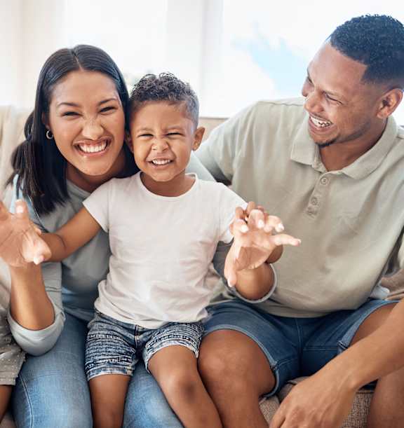 a family sitting on a couch smiling and waving to the camera