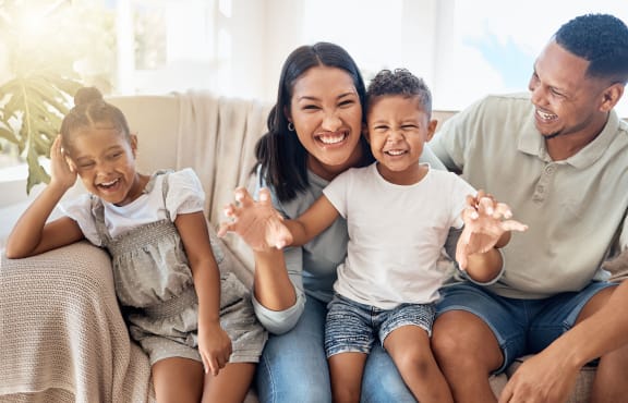 a family sitting on a couch smiling and waving to the camera