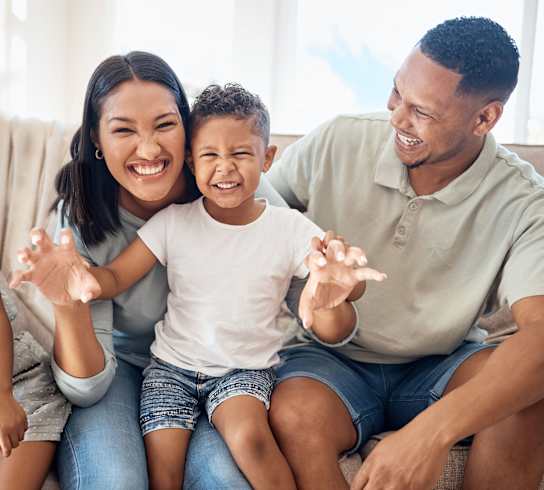 a family sitting on a couch smiling and waving to the camera at Emery Village, North Carolina, 28027