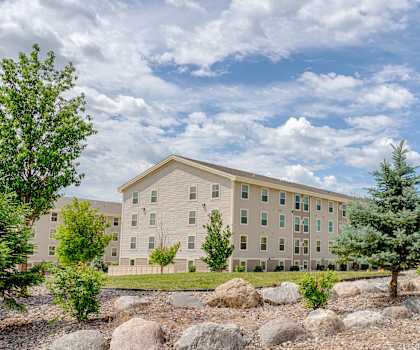 The large, grassy area with a pathway and trees behind the apartment buildings at Rockridge Apartment Homes. 