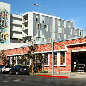 A red brick building with a white car parked in front.at Prizma, Los Angeles, CA
