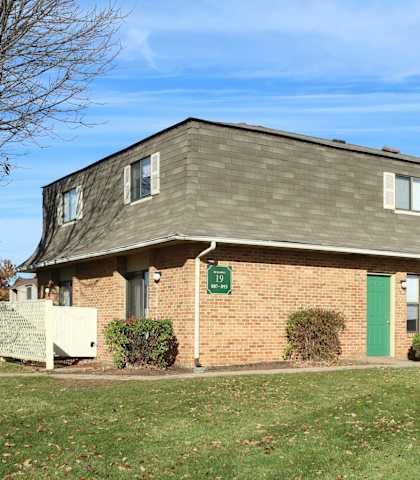 A small brick building with a green door and a sign on the front.