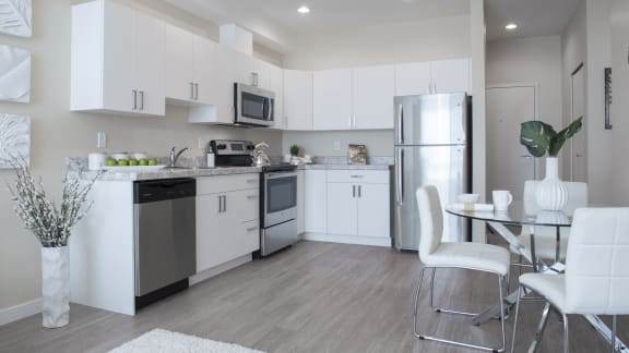 a kitchen with white cabinets and stainless steel appliances and a table and chairs