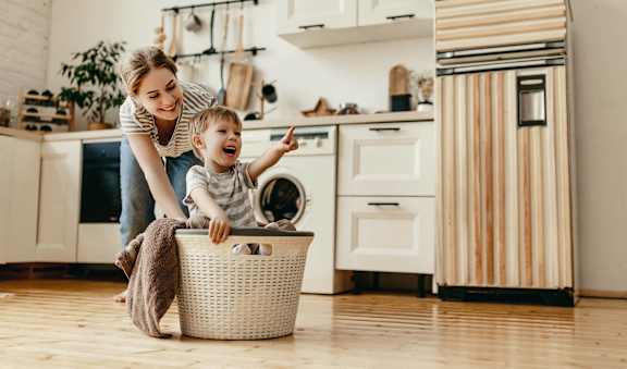 a woman and a child in a kitchen with a laundry basket