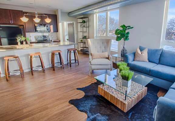 A living room with a blue couch and a glass coffee table.