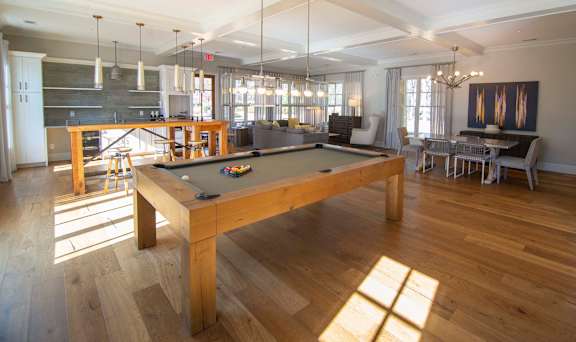 A pool table is in the middle of a room with a lot of windows.