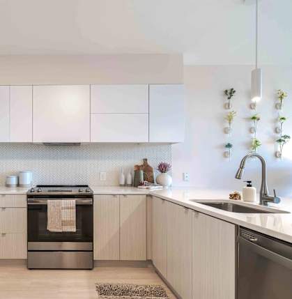 A modern kitchen with a refrigerator on the left and a sink on the right.