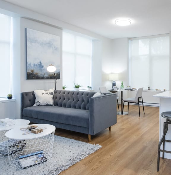 a living room with a couch and a kitchen with a bar and stools