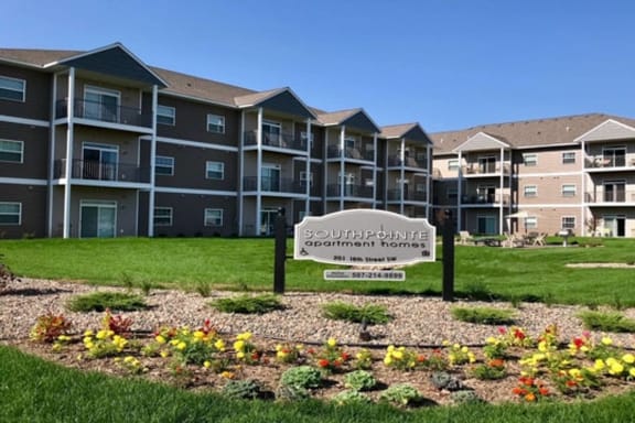 an architectural rendering of an apartment building with a sign in the middle of a garden
