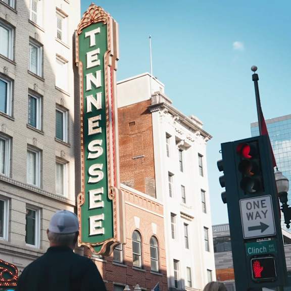 A man is walking under a Tennessee sign.