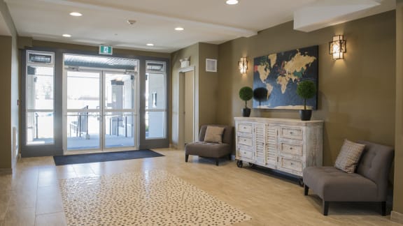 a lobby with two chairs and a chest of drawers and a map of the