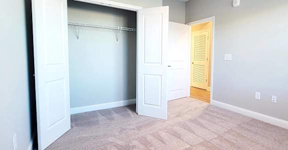 A room with a white door and a carpeted floor.