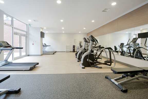 a gym with various cardio equipment on the floor and a window