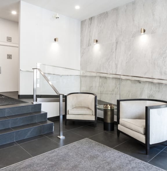 a lobby with two chairs and a staircase and a marble wall