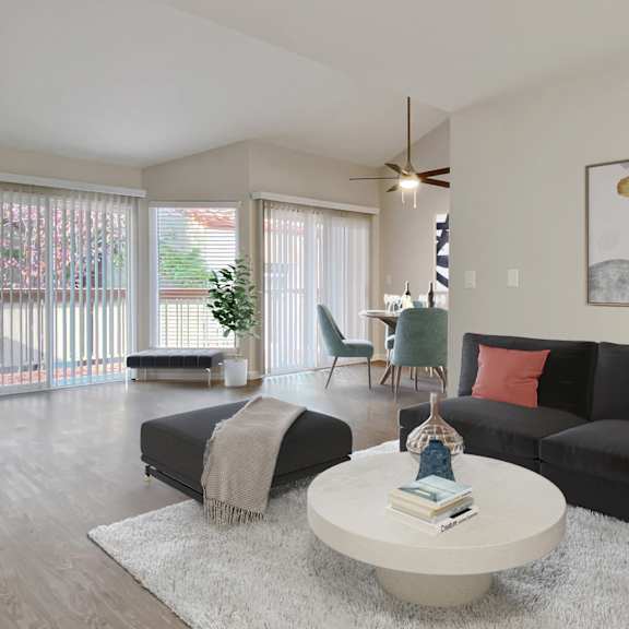 A living room with a black couch, a white coffee table, and a ceiling fan.
