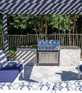 a patio with a grill and blue and white furniture