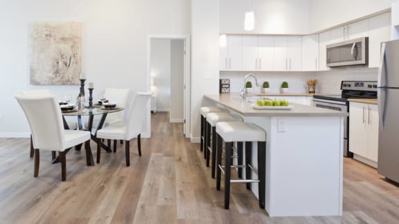 a kitchen and dining room with white cabinets and a table with white chairs
