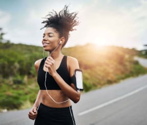 a young woman running down a road with headphones and a smart phone