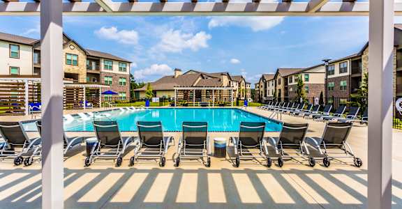 our apartments have a large swimming pool with chairs at The McKenzie Park Apartments, Little Rock, 72223