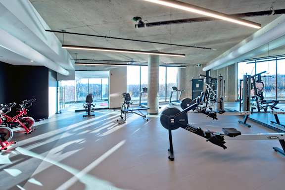 A gym with a variety of exercise equipment including treadmills, stationary bikes, and weight machines.