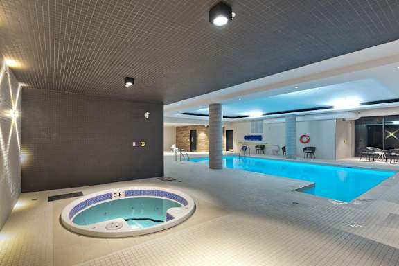 A modern indoor swimming pool area with a hot tub.