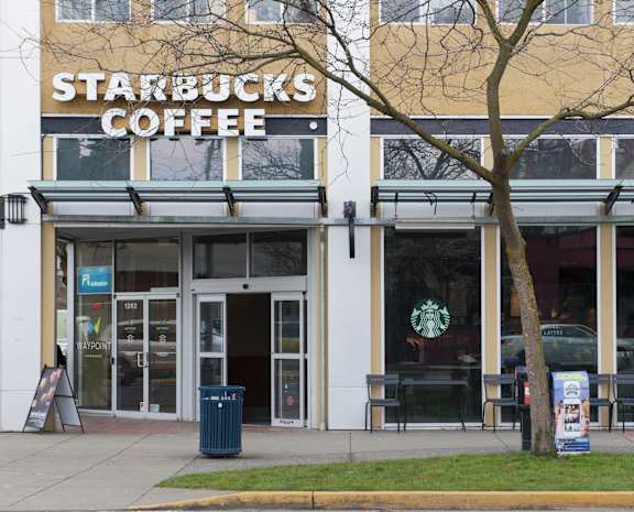 the front of a starbucks coffee building with a tree in front of it