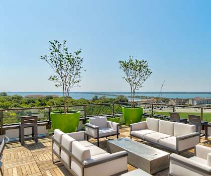 The rooftop lounge with couches, tables, chairs, and a view overlooking the water at Florence at the Harbor. 